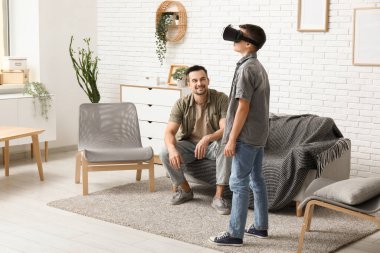 Babası ve VR gözlüklü küçük oğlu evde eğleniyorlar.