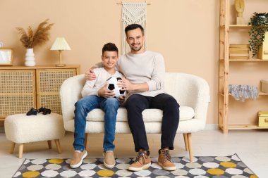 Mutlu baba ve küçük oğlu evde kanepede futbol topuyla.