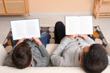 Baba ve küçük oğlu evde yerde kitap okuyorlar.