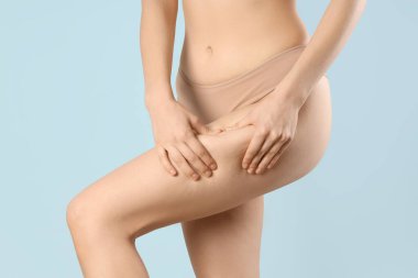 İç çamaşırlı, güzel bir kadın. Mavi arka planda selülit sorunu var.