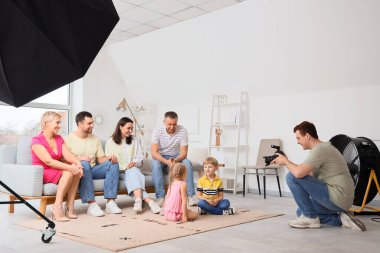 Stüdyoda küçük çocuklu aile fotoğrafı çeken erkek fotoğrafçı.