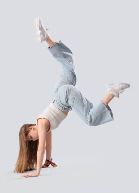 Gri arka planda hip-hop yapan güzel bir genç kadın.