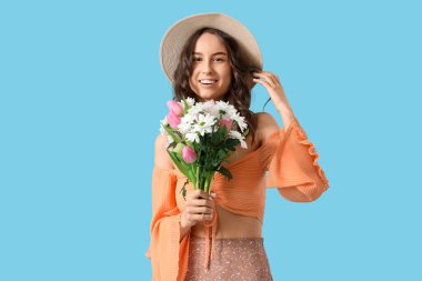 Mavi arka planda bahar çiçekleri olan şapkalı güzel bir kadın.