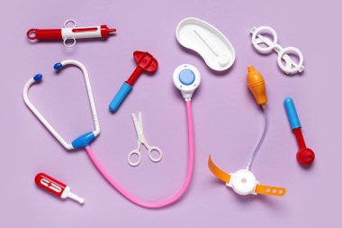 Termometresi olan oyuncak steteskop ve leylak arka planında refleks çekici. Üst görünüm