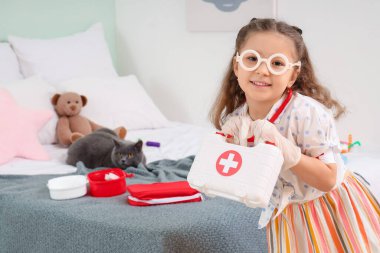 Evde ilk yardım çantası ve İngiliz kedisi olan sevimli küçük bir kız.