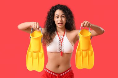 Genç ve güzel afro-amerikan bayan cankurtaran kırmızı arka planda yüzgeçleri ile