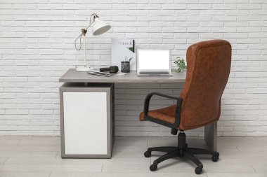 Çalışma yeri, dizüstü bilgisayarı ve koltuğu olan beyaz modern ofisin şık iç tasarımı