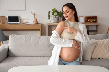 Evde aşıdan sonra yamayla gezen hamile bir kadın.