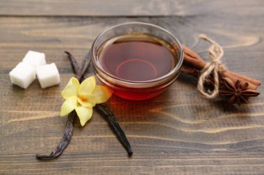 İçinde vanilya özü ve ahşap arka planda baharatlar olan kompozisyon.