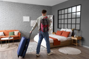 Çantalı bir erkek turist otel odasında yürüyor.