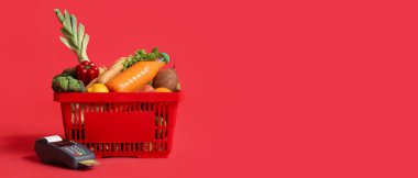 Kırmızı arka planda yiyecek ve ödeme terminali dolu alışveriş sepeti metin için yer var