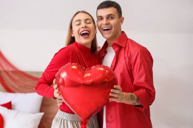 Young couple with balloon in bedroom on Valentine's Day