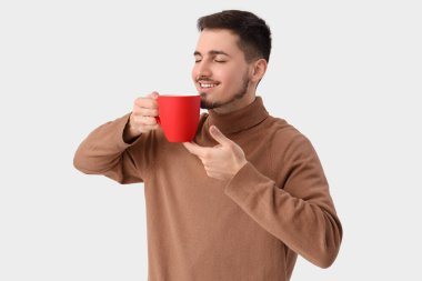 Beyaz arka planda bir fincan çayı olan genç adam.