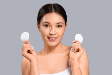 Gri arka planda pamuk pedleri olan genç Asyalı kadın, yakın plan.