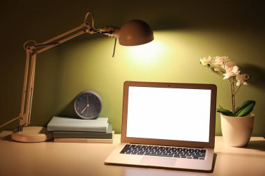 Parlak lambalı, dizüstü bilgisayarlı, saatli ve çiçekli işyeri