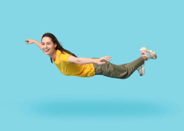 Mavi arka planda uçan neşeli genç kadın