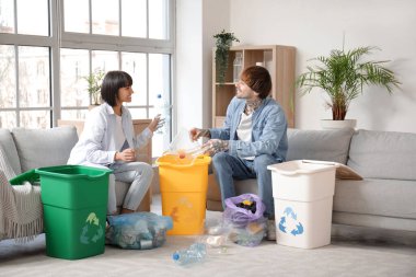 Evlerinde çöp kutularını düzenleyen genç bir çift. Geri dönüşüm kavramı