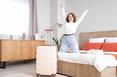 Otel odasında yatakta mutlu bir bayan turist.