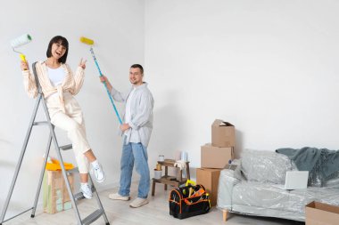 Yeni evlerinde tamirat sırasında boya silindirli genç bir çift.