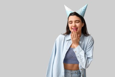 Gri arka planda parti şapkalı güzel bir kadın.