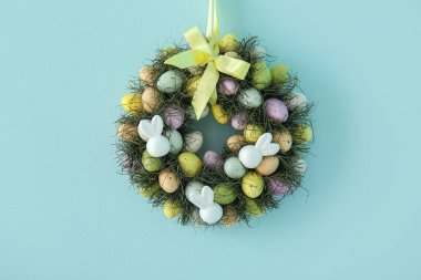Mavi duvarda yumurtalarla süslenmiş güzel Paskalya çelengi