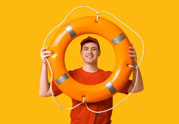 Portrait of male lifeguard with ring buoy on yellow background