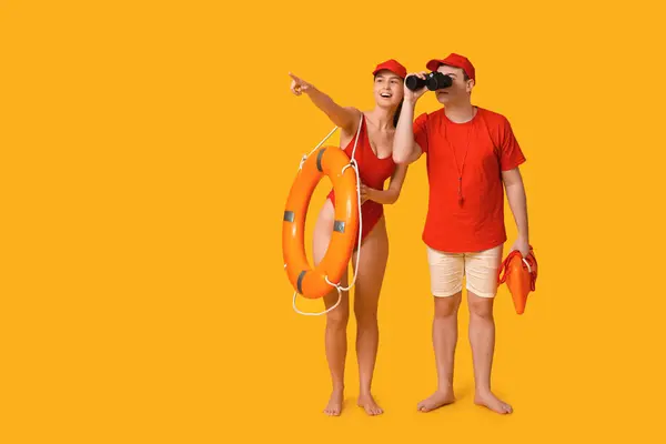 Lifeguards with ring buoy, rescue tube and binoculars spotted something on yellow background