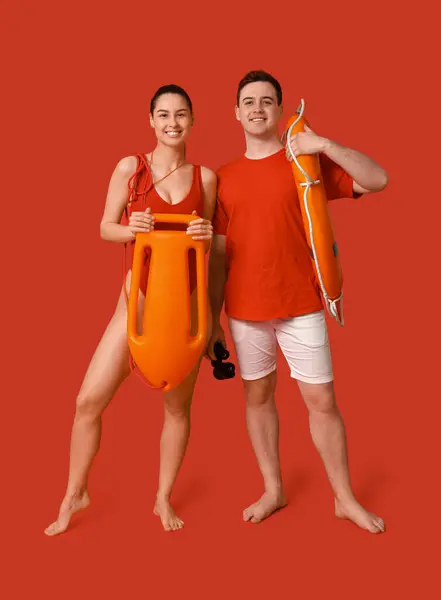 Lifeguards with ring buoy, rescue tube and binoculars on red background