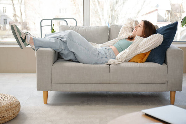 Красивая молодая женщина отдыхает на диване в гостиной