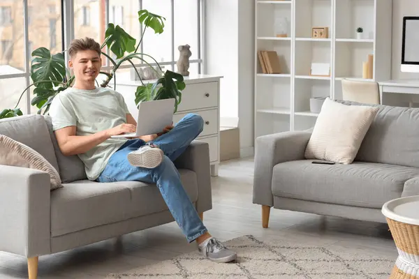 stock image Handsome young man using laptop on sofa at home