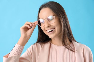 Mavi arka planda gözlüklü genç bayan, yakın plan.