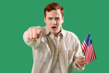 Amerikan bayrağı taşıyan genç adam yeşil arka plandaki izleyiciye bakıyor. Suçlama kavramı