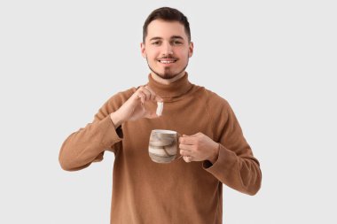 Beyaz arka planda bir fincan çay ve şekerli genç adam