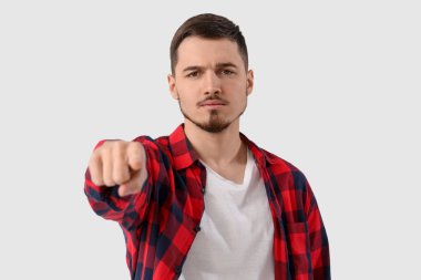 Genç adam beyaz arka plandaki izleyiciyi işaret ediyor, yakın plan. Suçlama kavramı