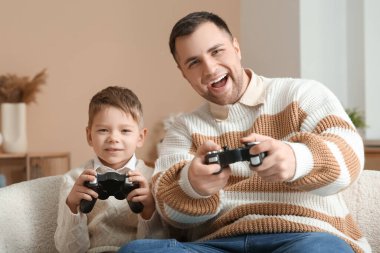Mutlu baba ve küçük oğlu evde video oyunu oynuyorlar.