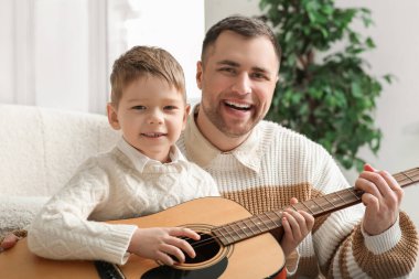 Mutlu baba ve küçük oğlu evde gitar çalıyorlar.