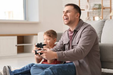 Mutlu baba ve küçük oğlu evde video oyunu oynuyorlar.