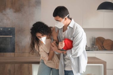 Young couple with first aid kit escaping from burning kitchen clipart