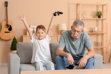 Büyükbaba ve küçük tatlı torunu evde video oyunu oynuyorlar.