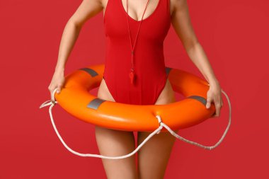 Yüzük şamandıralı ve kırmızı arka planda ıslık çalan kadın cankurtaran.