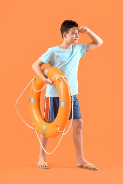 Turuncu arka planda yüzük şamandırası olan şirin bir çocuk.