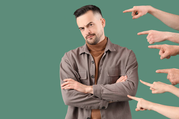 People pointing at young man on green background. Accusation concept