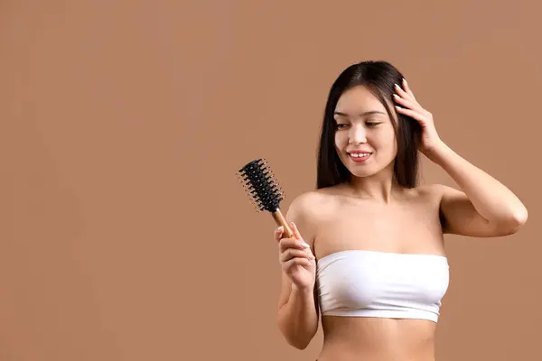美しい若い幸せなアジアの女性は茶色の背景に髪をブラッシング — ストック写真