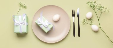 Açık yeşil arka planda hediyeler ve yumurtalarla güzel bir Paskalya masası.