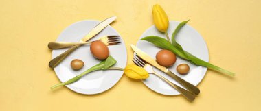 Sarı arka planda Paskalya yumurtaları ve lale çiçekleri olan masa ayarı