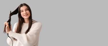 Gri arkaplanda saçlarını kıvıran güzel bir genç kadın ve mesaj için yeri var.