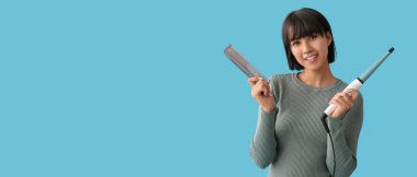 Saç maşası ve açık mavi arka planda tarağı olan güzel genç bir kadın.