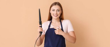 Bej arka planda saç maşası olan kadın kuaför.