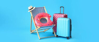 Güverte sandalyesi, bavullar ve plaj aksesuarları mavi arkaplandalar ve metin için yer var.