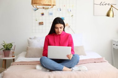 Yatak odasında dizüstü bilgisayarla çalışan serbest çalışan bir kadın.